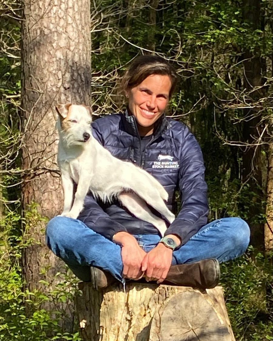 Marie Riesenkampff sitzt mit ihrem Hund auf einem Baumstumpf im Wald